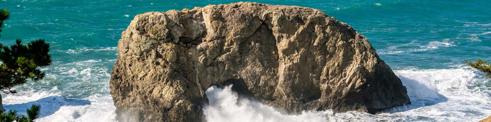 Pictured: Large rock in the sea with waves in Oregon.